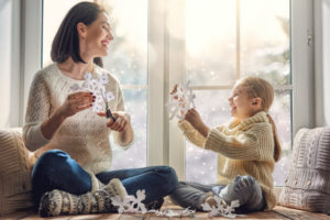 Mother And Daughter Cutting Out Paper Snowflakes